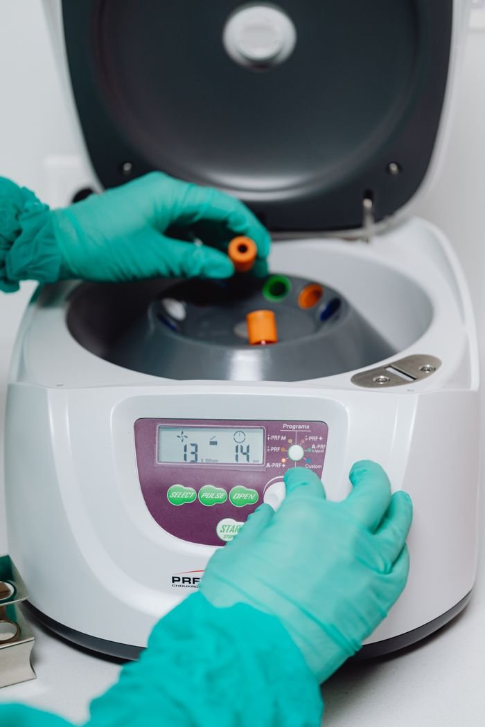 about-us Close-up of a laboratory technician operating a centrifuge machine for sample processing.