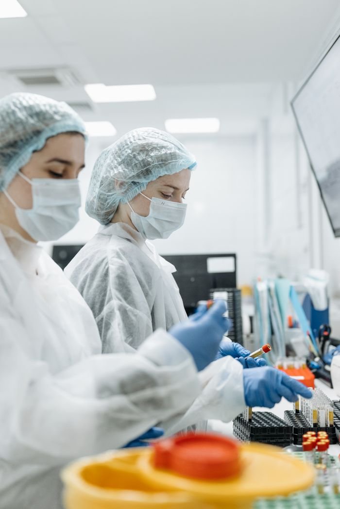 services-02 Two scientists in PPE conducting experiments in a modern laboratory.